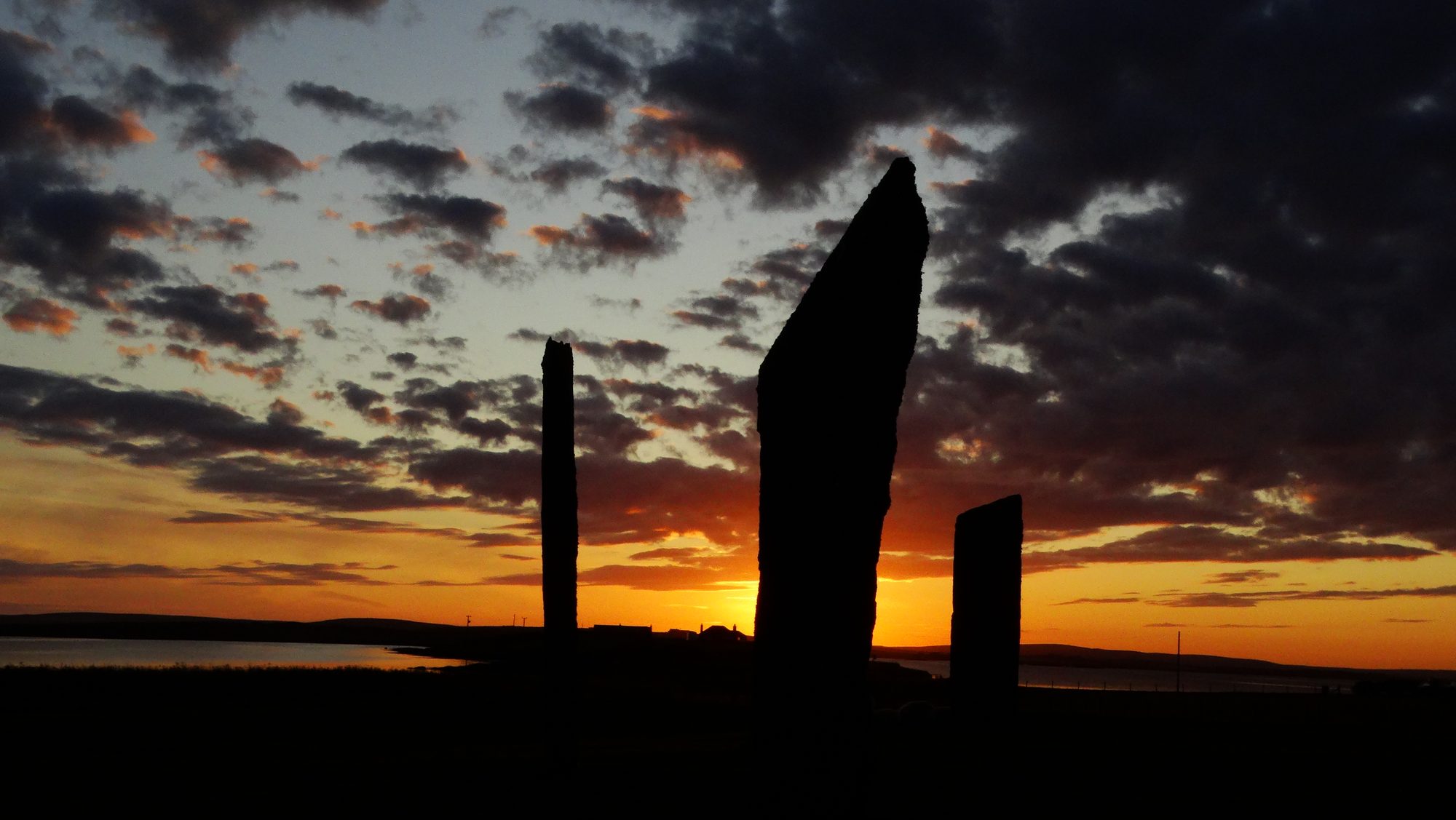 The standing stones of Stenness in Orkney, dark against a low sunset sky